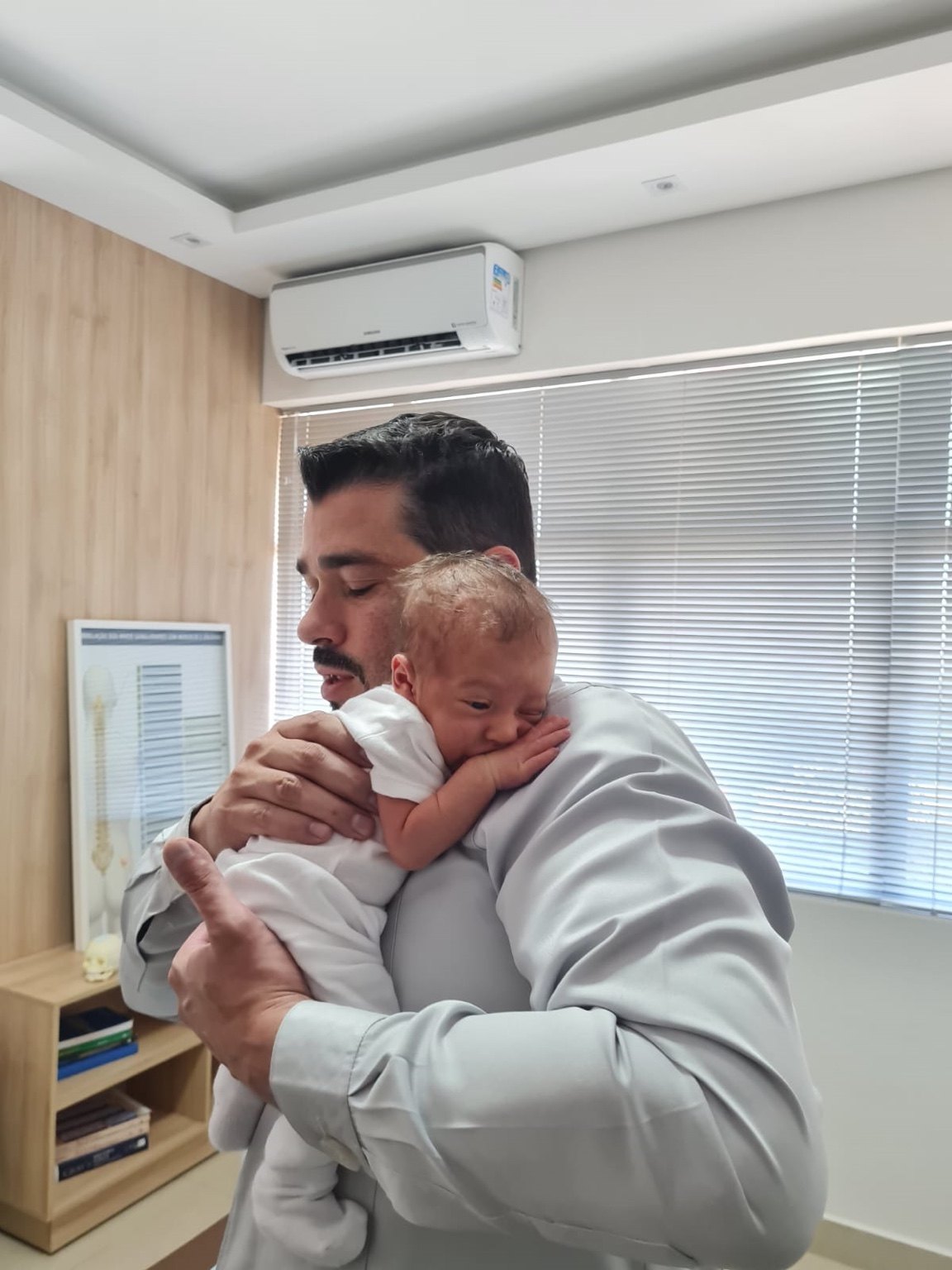 Dr. Vinicius Polizer segurando bebê no consultório